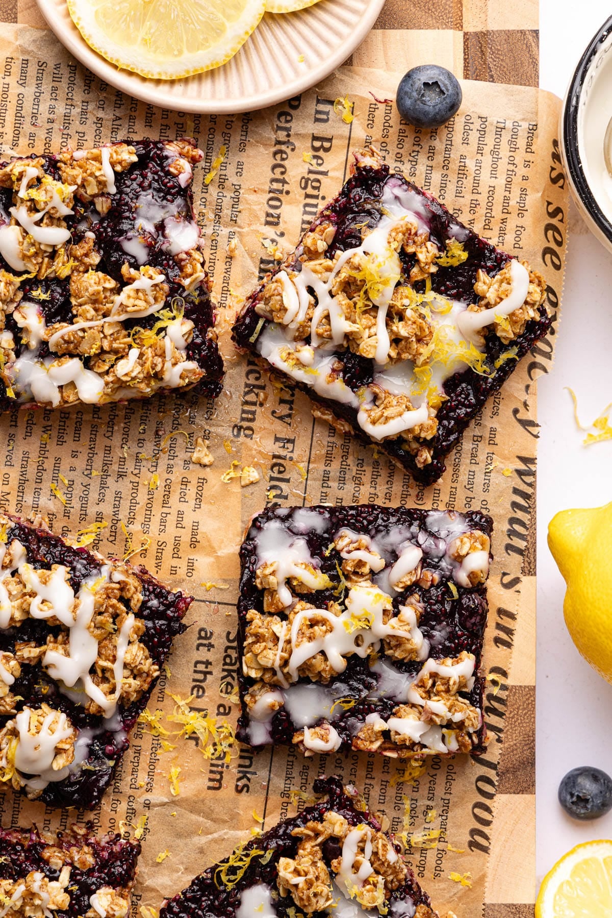 No Bake Lemon Blueberry Bars on parchment paper with some fresh blueberries garnished on the side.
