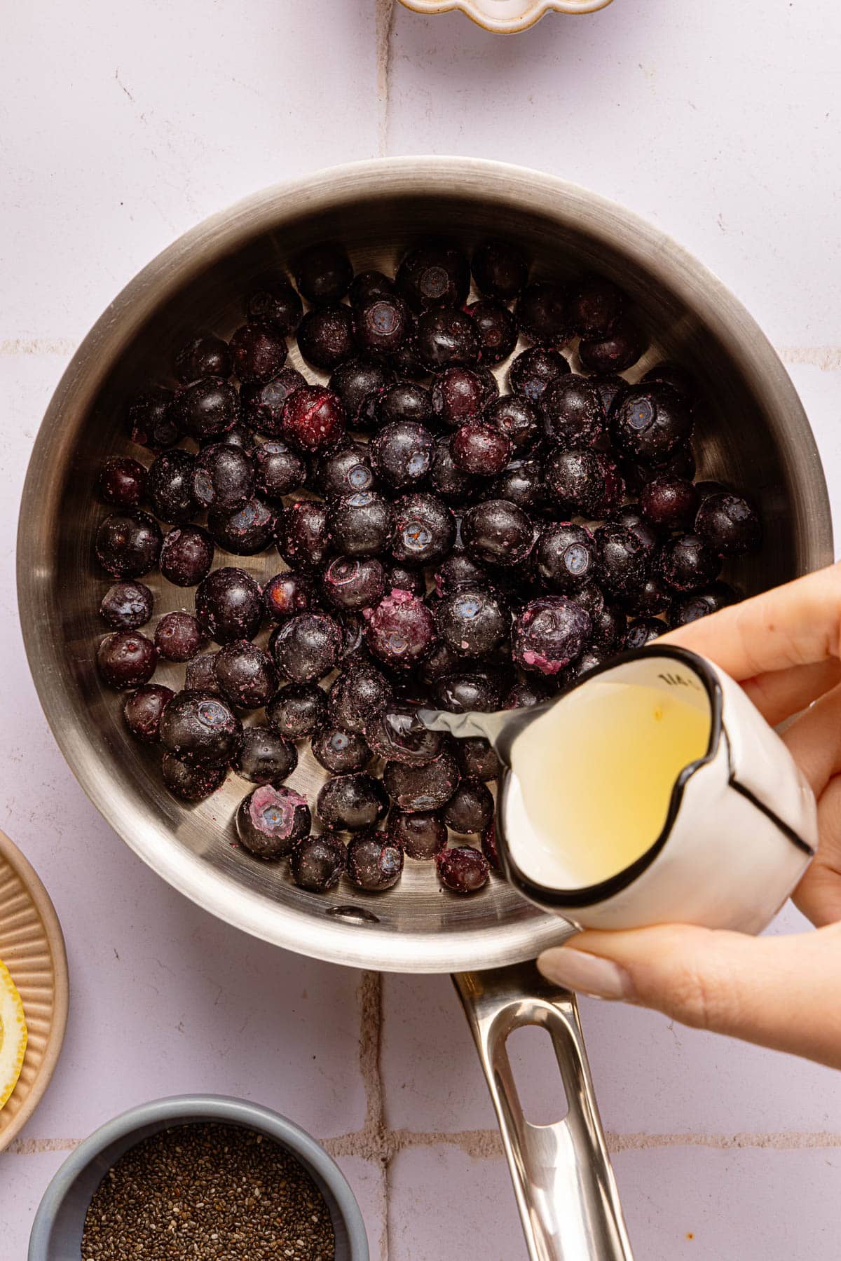 Pouring lemon juice into the pot of blueberries.