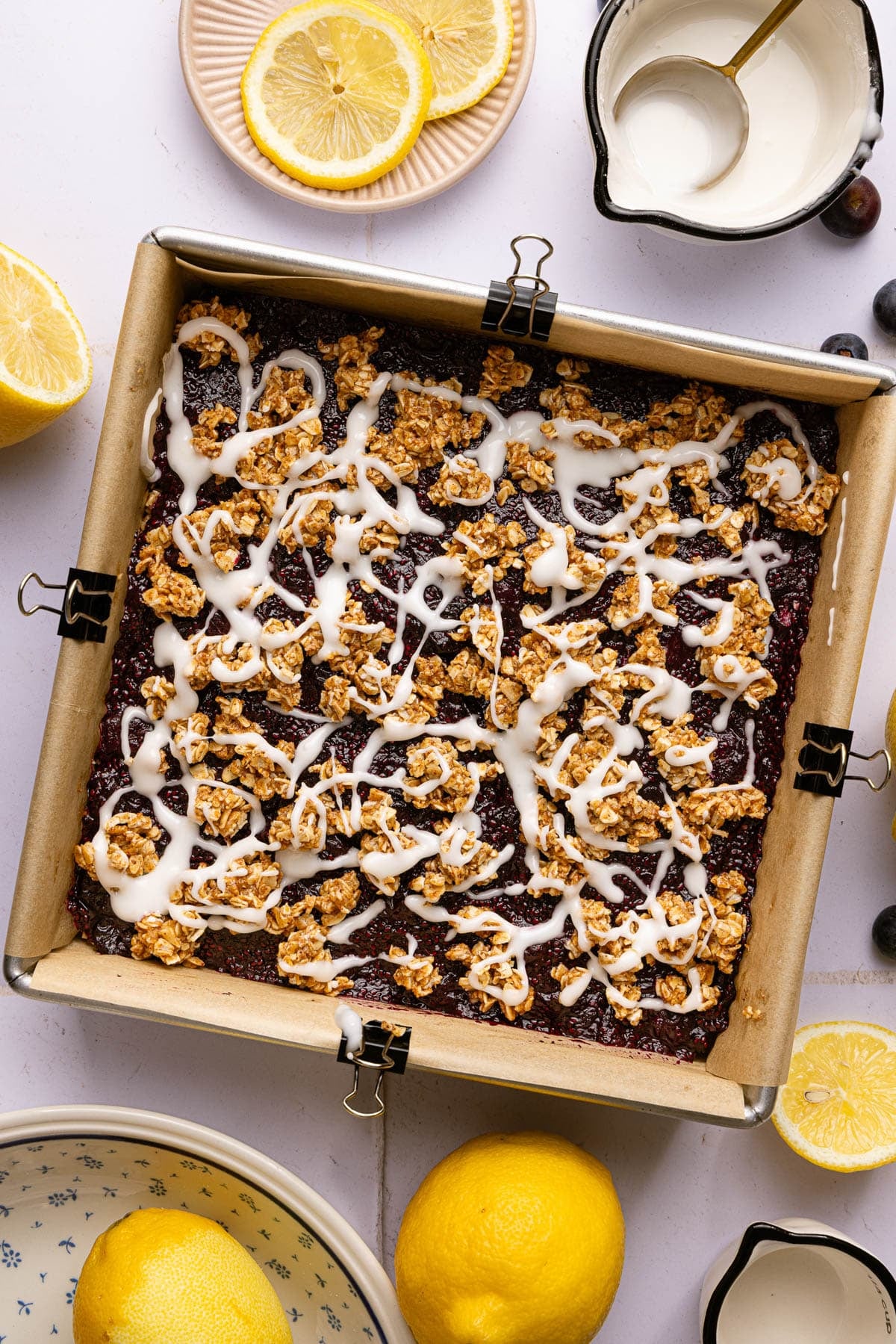 The blueberry lemon bars with lemon glaze in a baking pan.