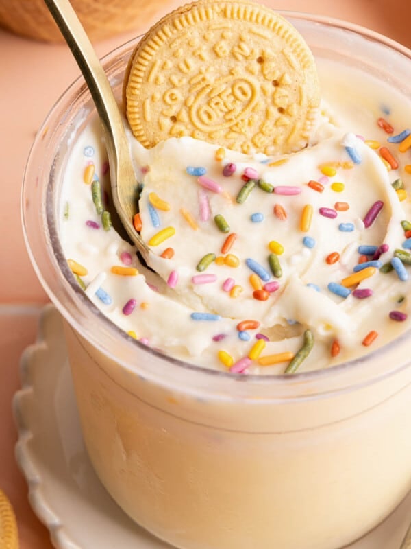 Ninja creami cake batter ice cream in a container with a spoon and oreo cookie in it.