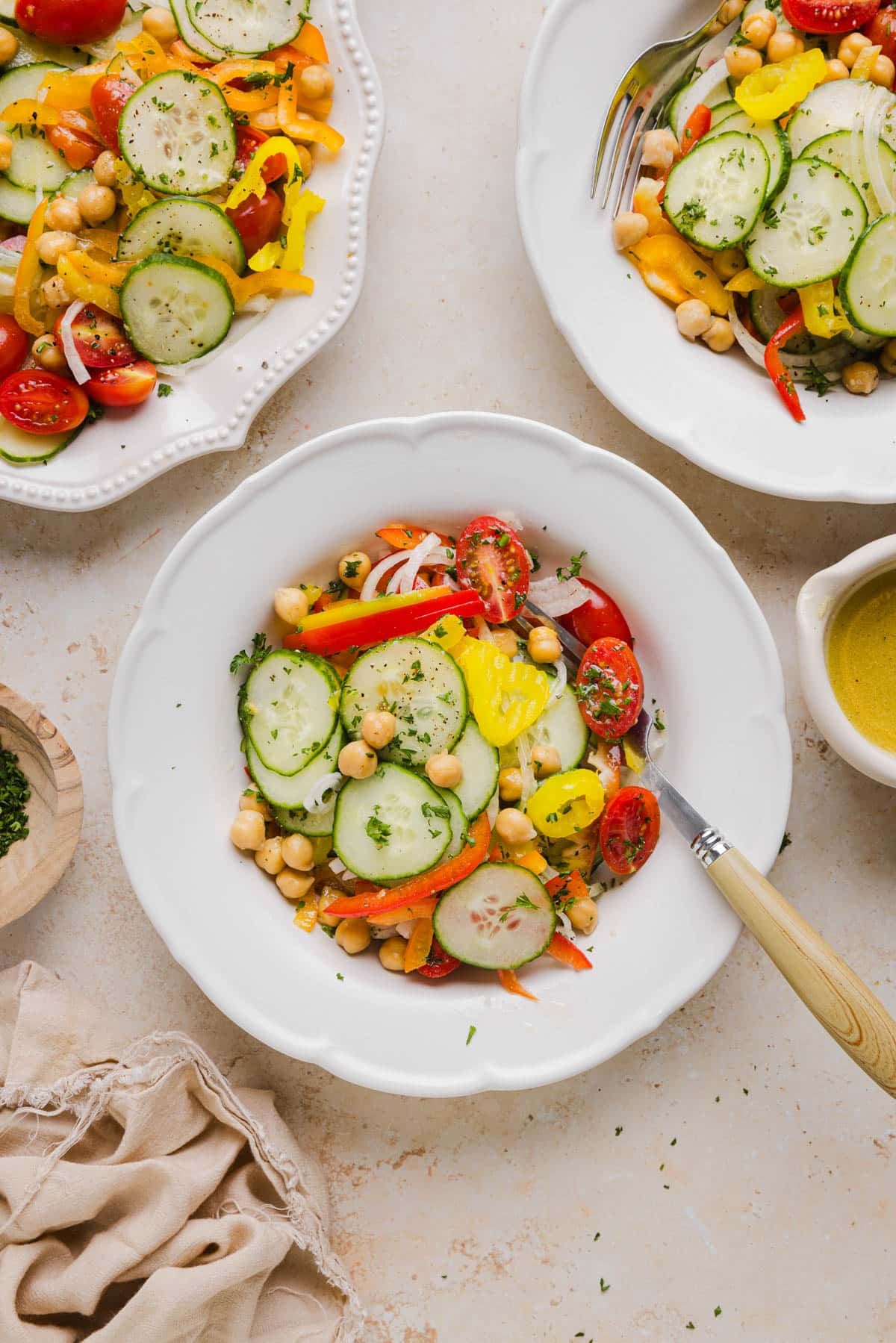 A white bowl with the mixed salad and the remaining salad in a platter on the side.