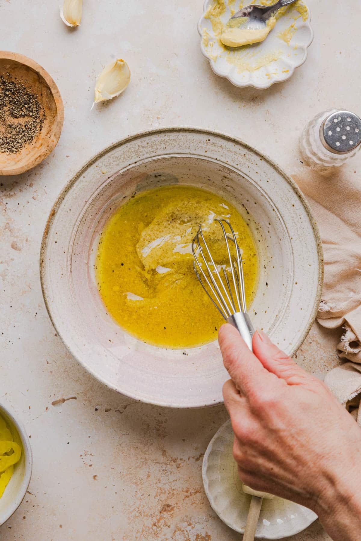 Whisking together all of the ingredients for the salad dressing in a white bowl.