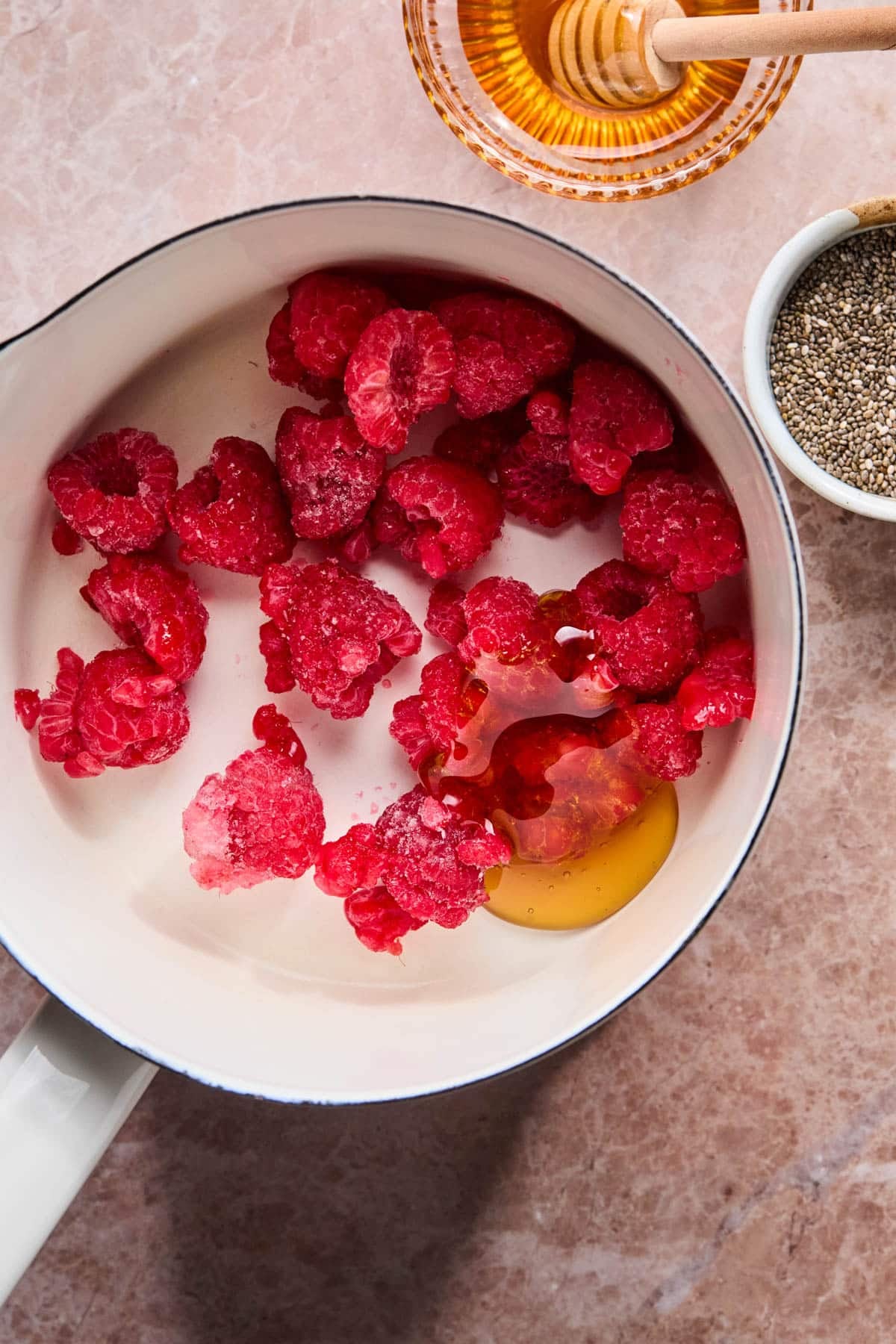 The raspberries and honey in a saucepan before cooking down.