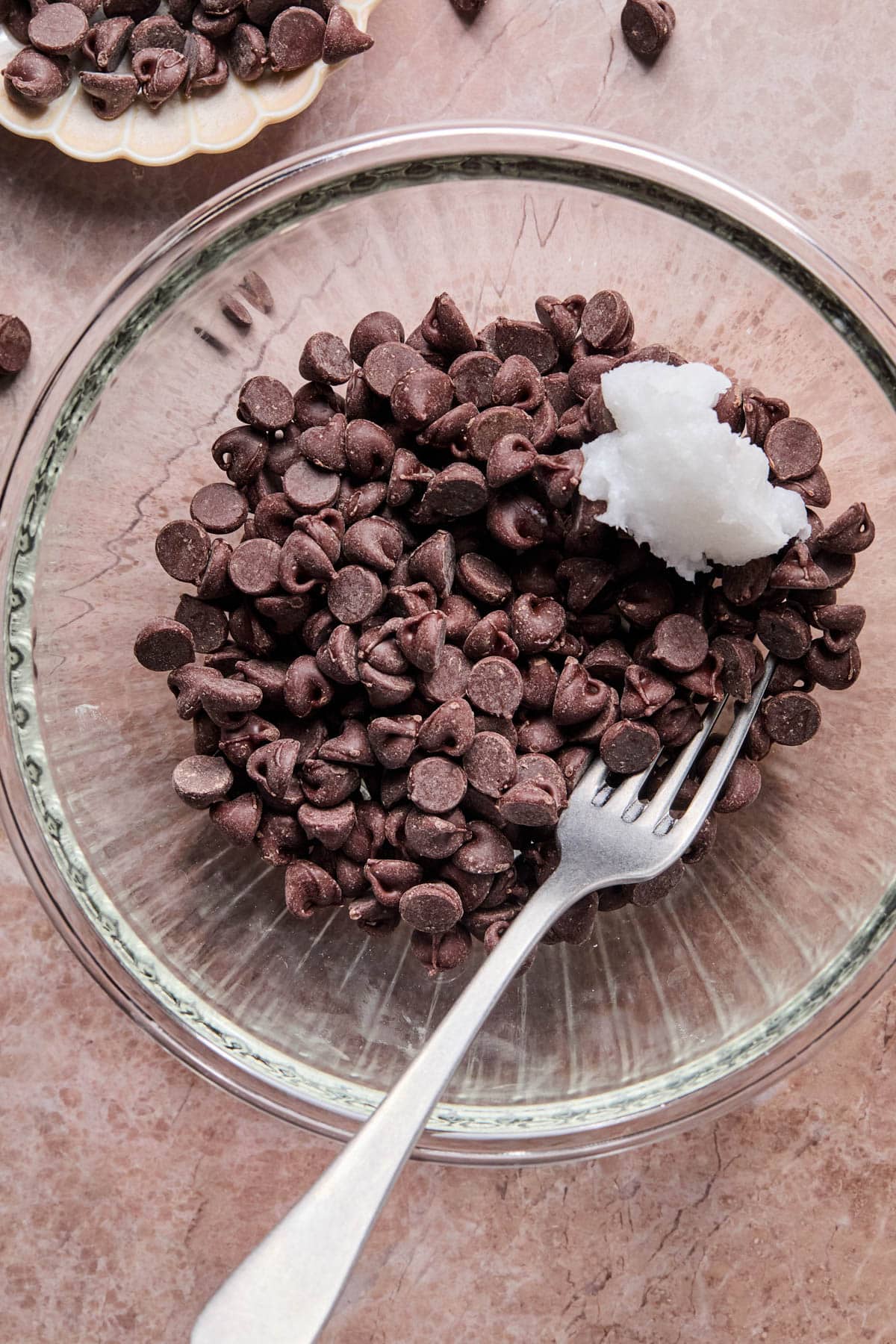 The chocolate chips and coconut oil in a glass bowl before melting.