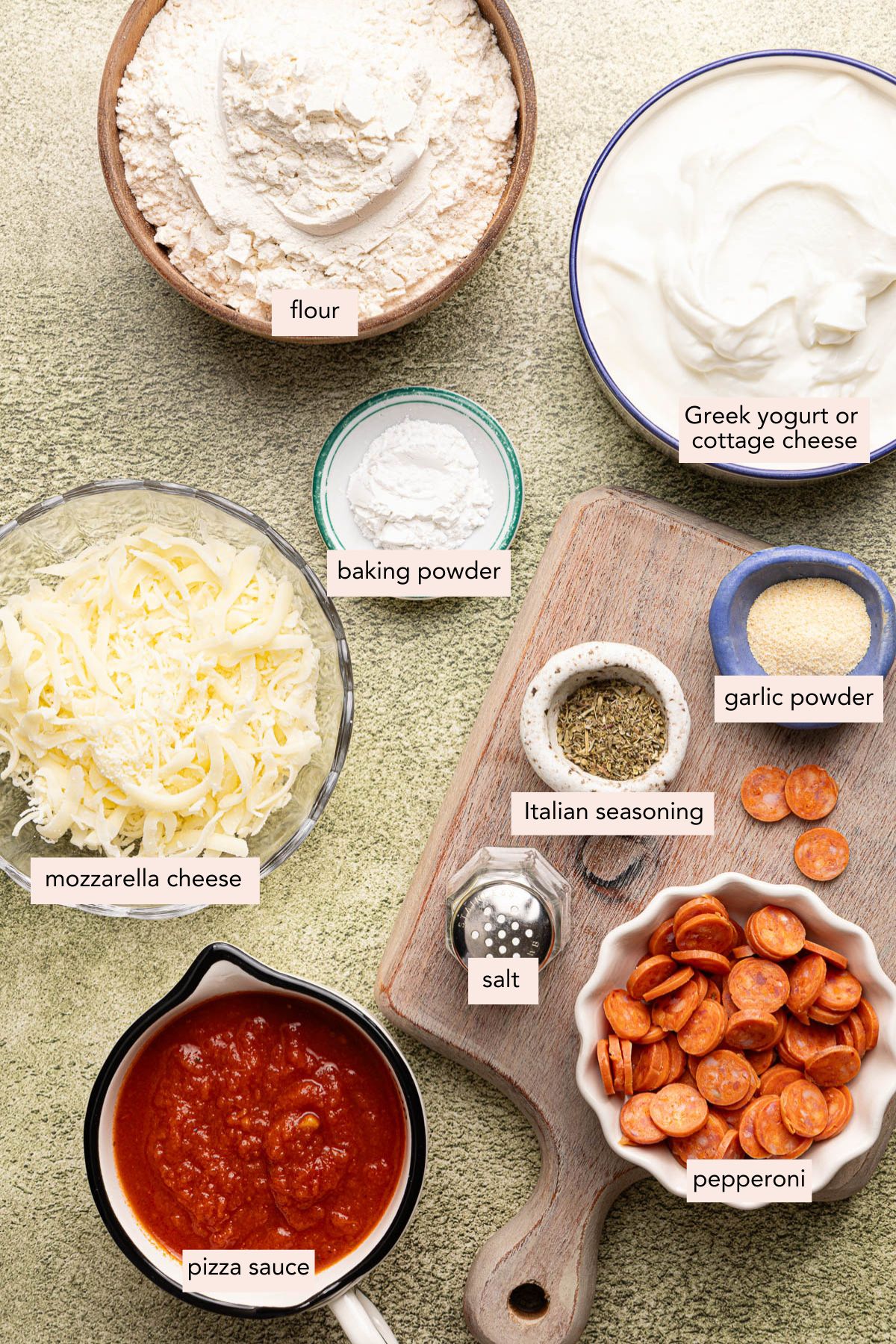 All of the ingredients for pizza cups in bowls on a countertop.