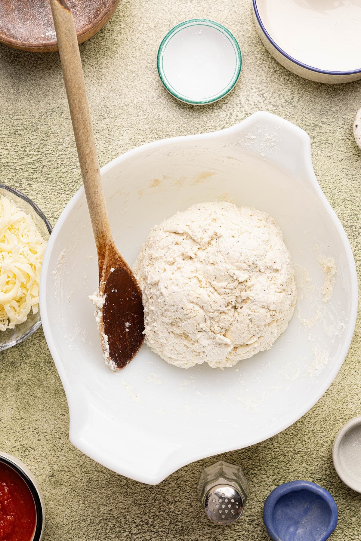 A dough ball in a large white bowl on a countertop.