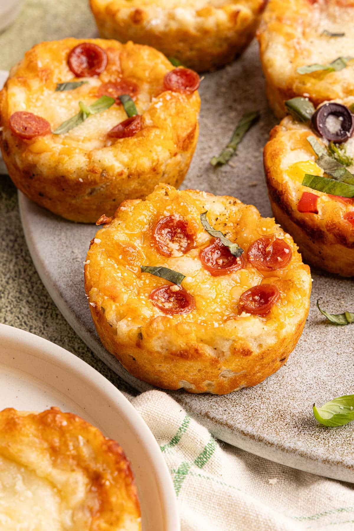 Two pizza bites sitting on a serving board, both with mini pepperoni on top.