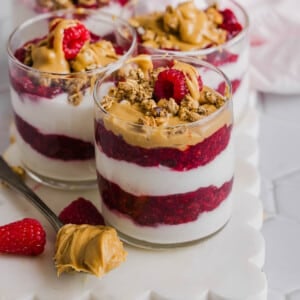 Four peanut butter and jelly yogurt parfaits sitting on a white serving platter.