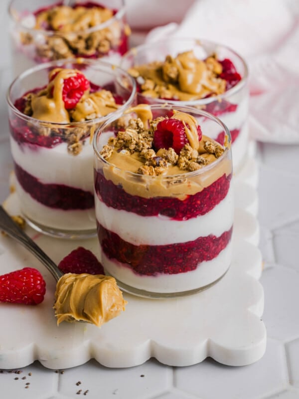 Four peanut butter and jelly yogurt parfaits sitting on a white serving platter.