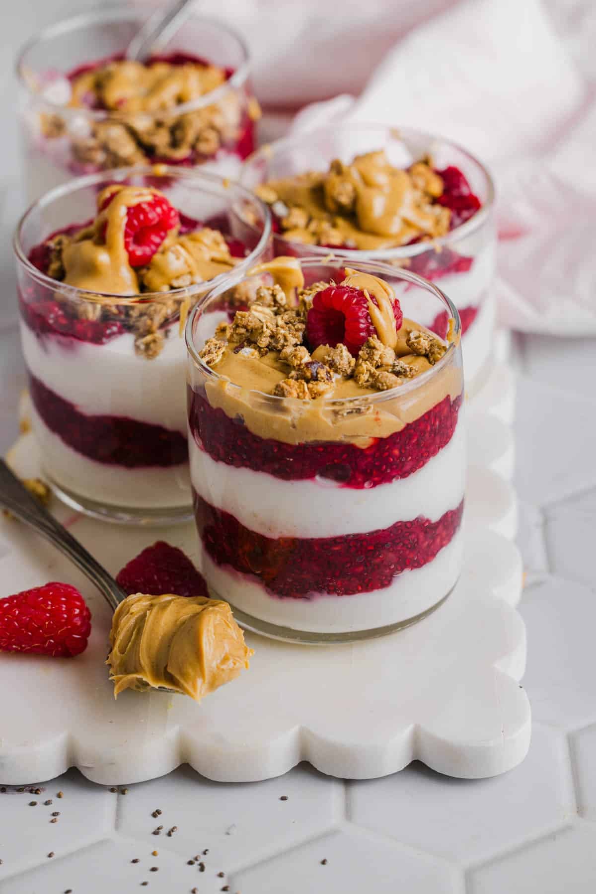 Four peanut butter and jelly yogurt parfaits sitting on a white serving platter.