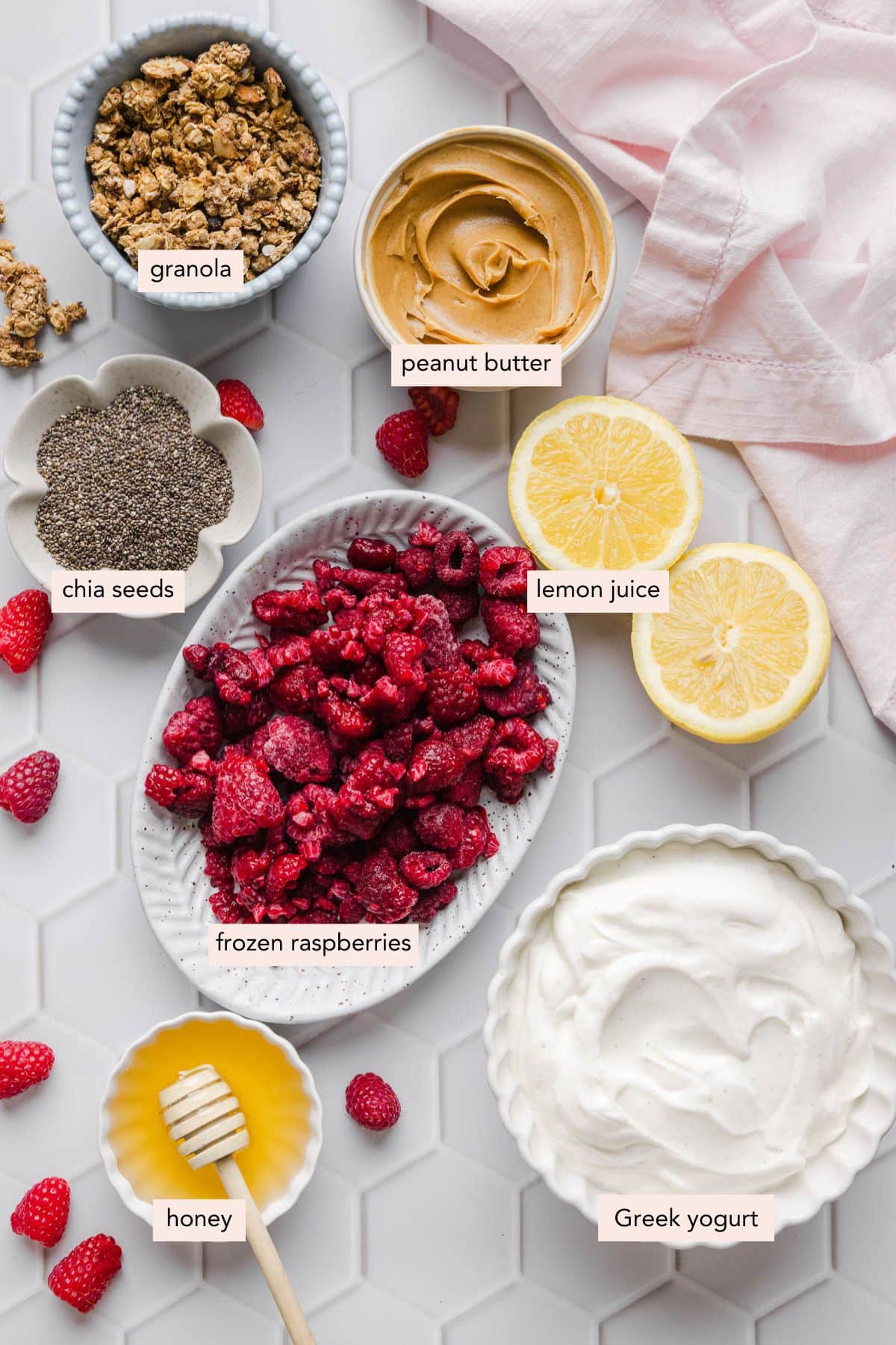 All of the ingredients for peanut butter and jelly yogurt parfaits in bowls on a white countertop.