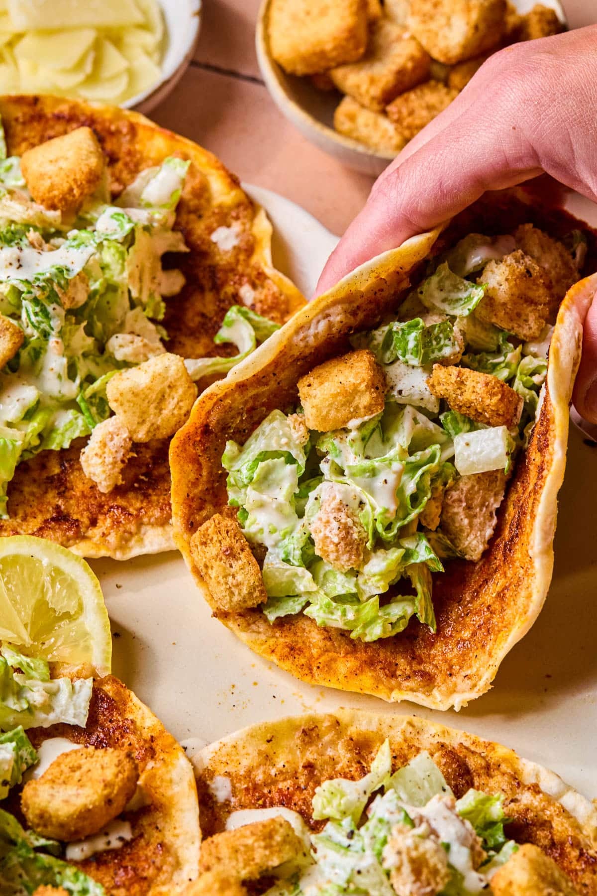 A hand holding the folded chicken caesar smash taco.