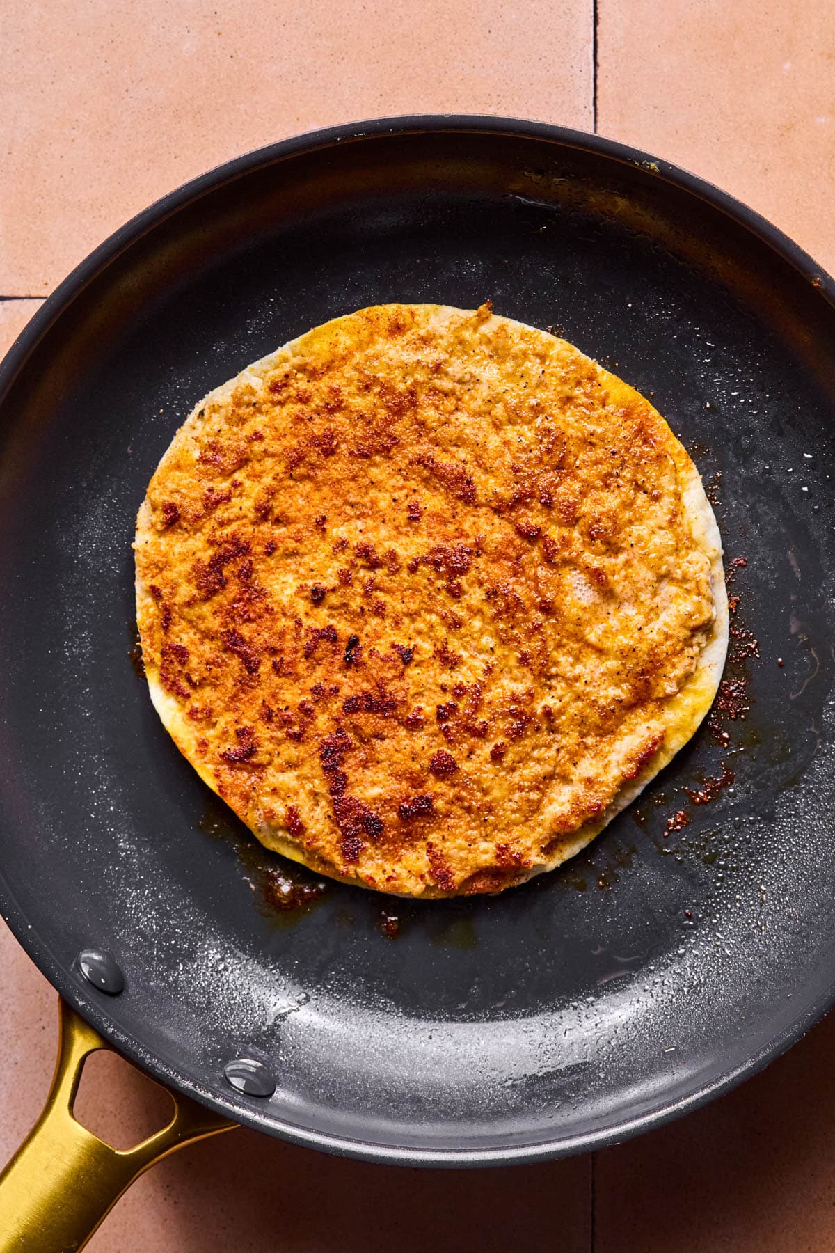 The tortilla flipped in the skillet so the browned chicken side is up.