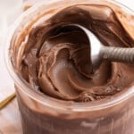 Ninja creami chocolate protein ice cream in a pint container with an ice cream scoop sitting in it.