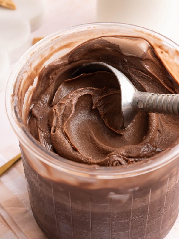 Ninja creami chocolate protein ice cream in a pint container with an ice cream scoop sitting in it.