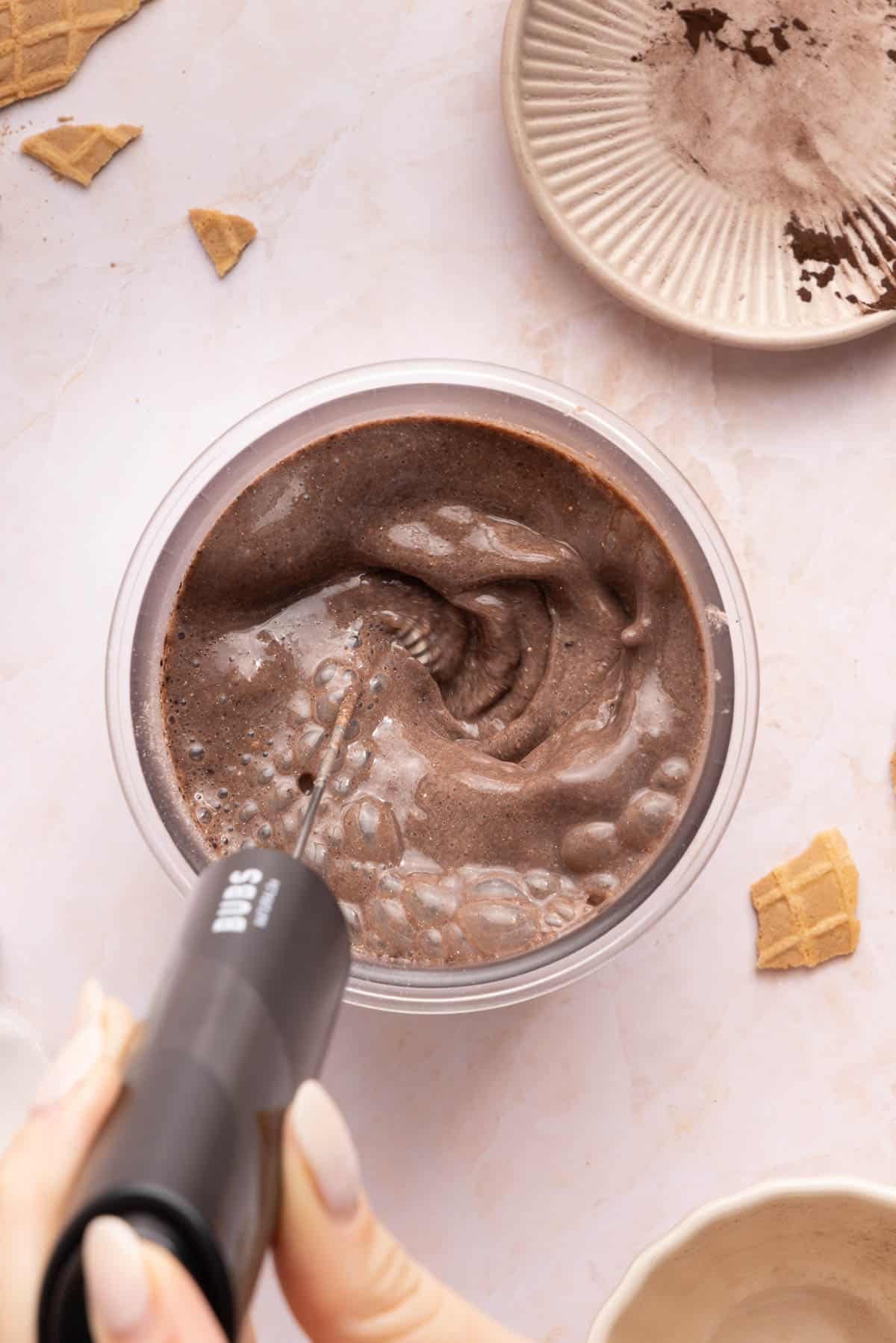 A frother mixes the ingredients in the container until combined.