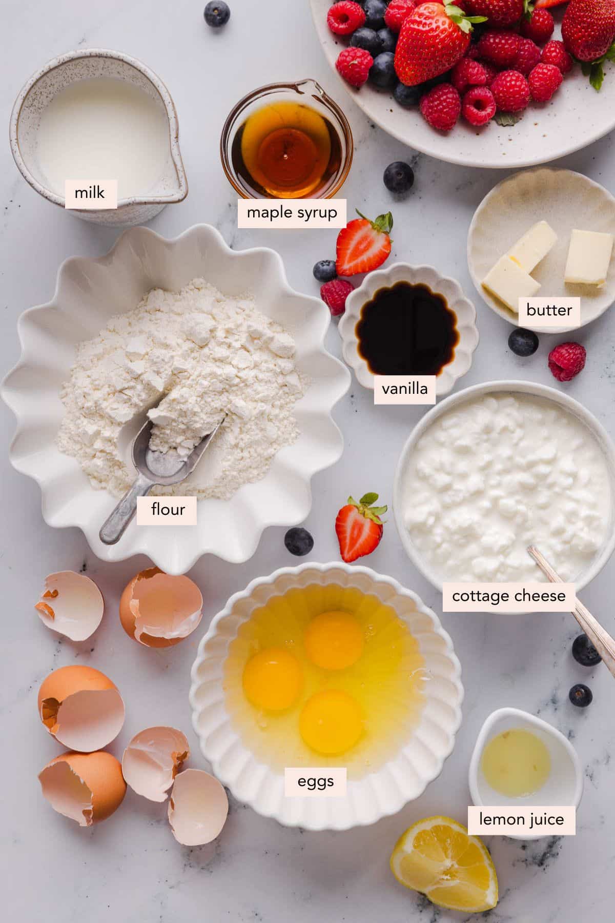 All of the ingredients for cottage cheese crepes in bowls on a white countertop.
