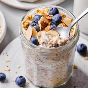 A spoon scoops some vanilla overnight oats from a jar.