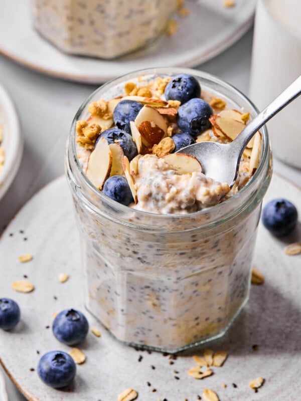 A spoon scoops some vanilla overnight oats from a jar.