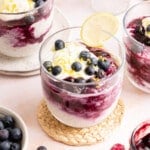 Fresh blueberries on top of lemon blueberry overnight oats in a glass jar with a lemon slice garnished on the rim.