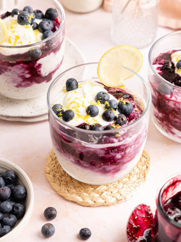 Fresh blueberries on top of lemon blueberry overnight oats in a glass jar with a lemon slice garnished on the rim.