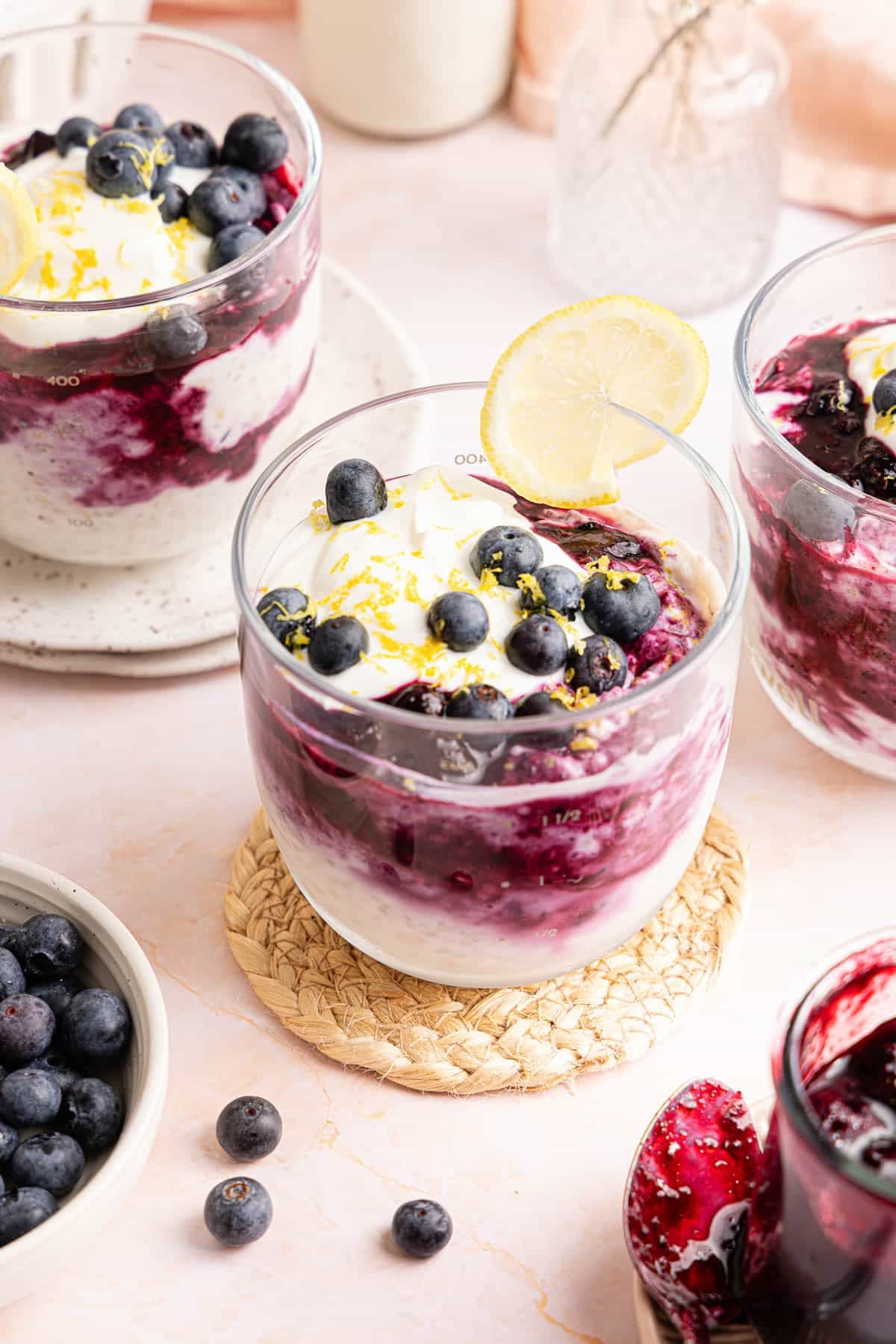 Fresh blueberries on top of lemon blueberry overnight oats in a glass jar with a lemon slice garnished on the rim.