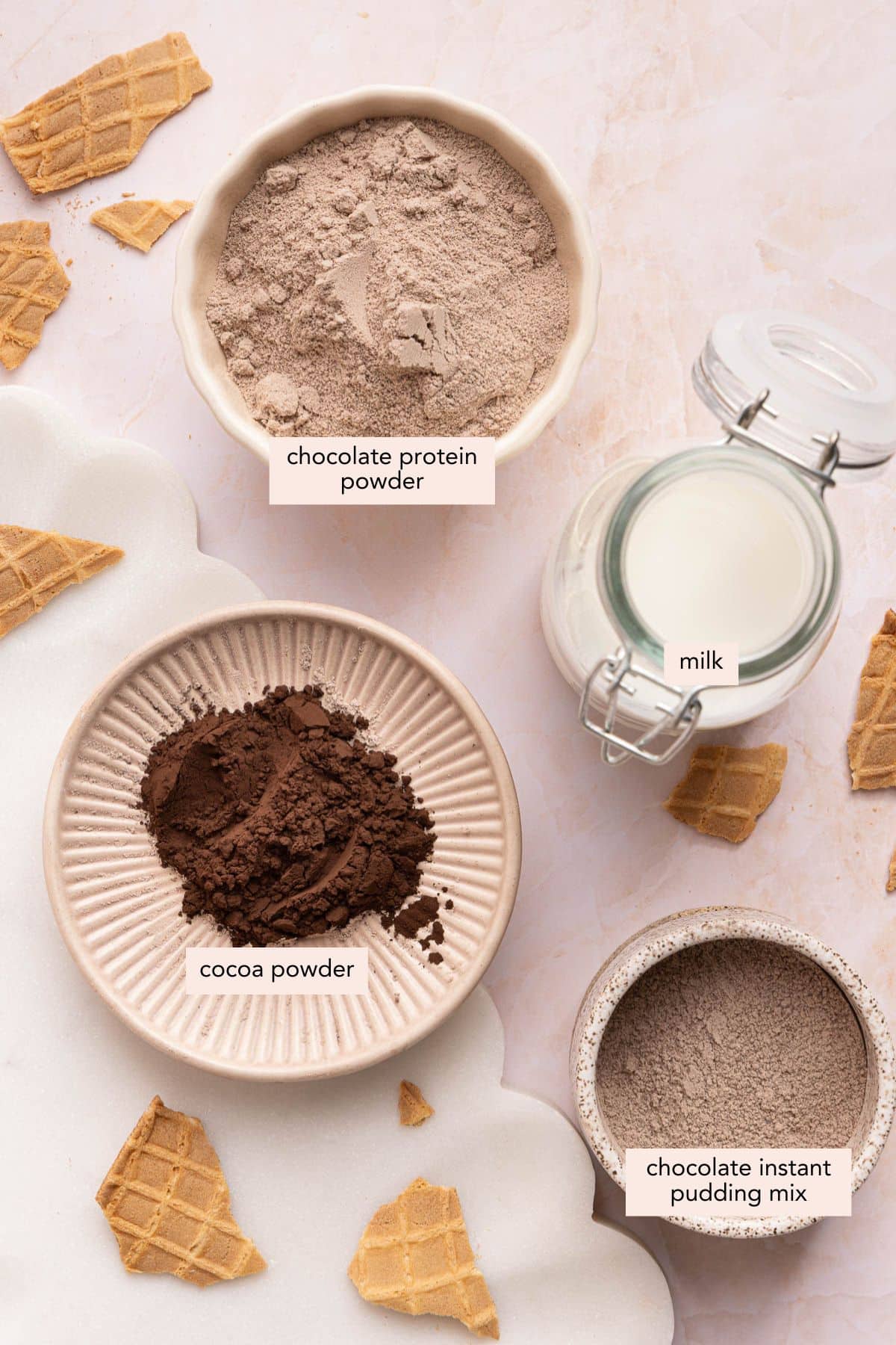 All of the ingredients for chocolate protein ice cream in the ninja creami in bowls on a countertop.