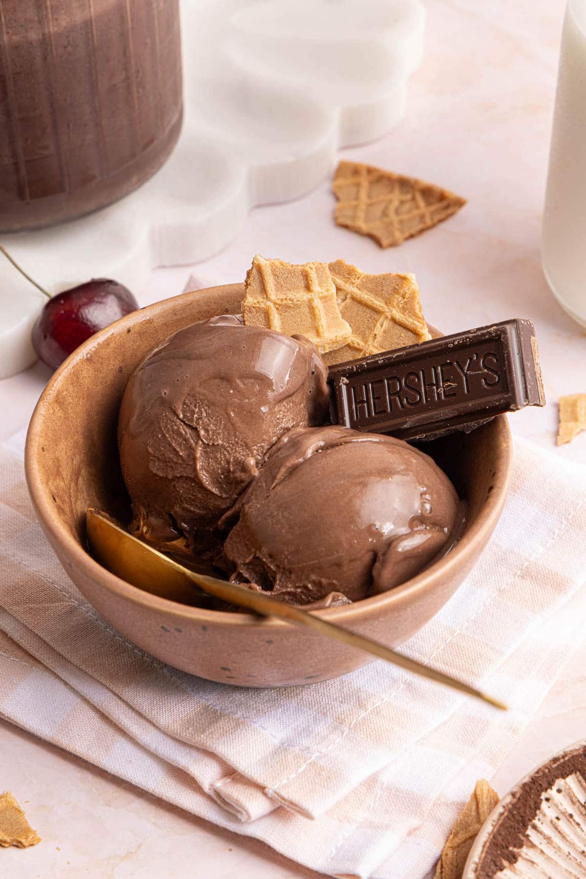 Two scoops of chocolate protein ice cream in a bowl with a piece of hersheys chocolate garnished on the side.