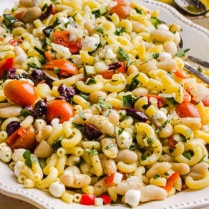 Pasta and bean salad on a white serving platter on a countertop.