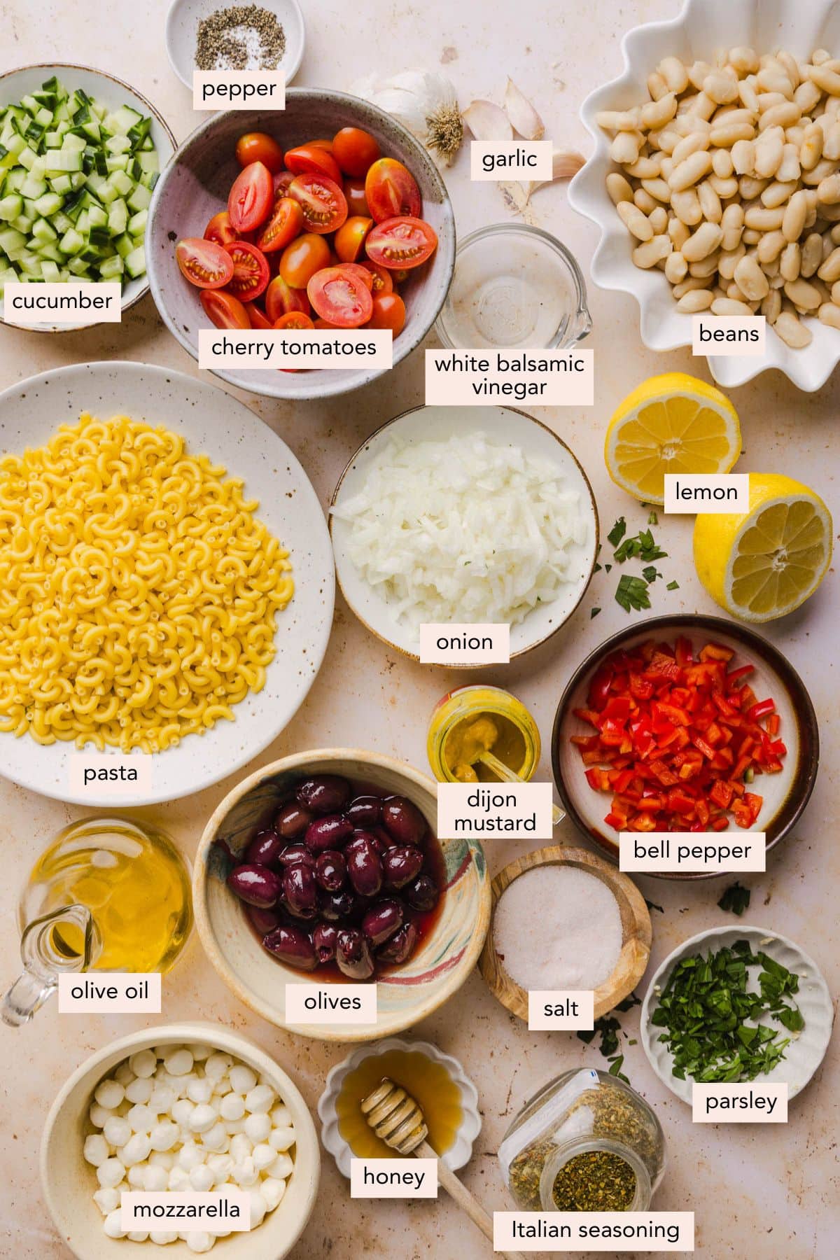 All of the ingredients for pasta bean salad in bowls on a countertop.