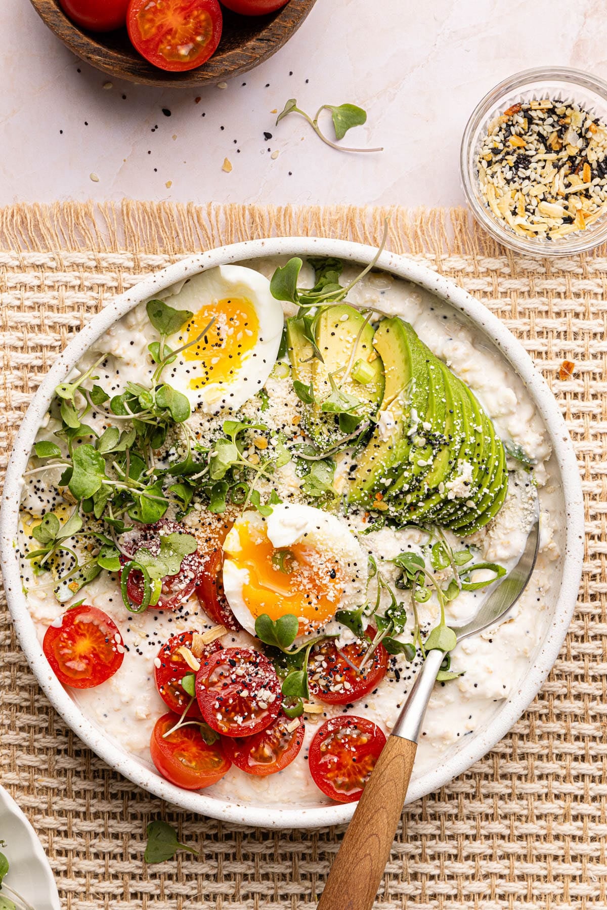A bowl filled with oats and all the savory toppings with a spoon in it.