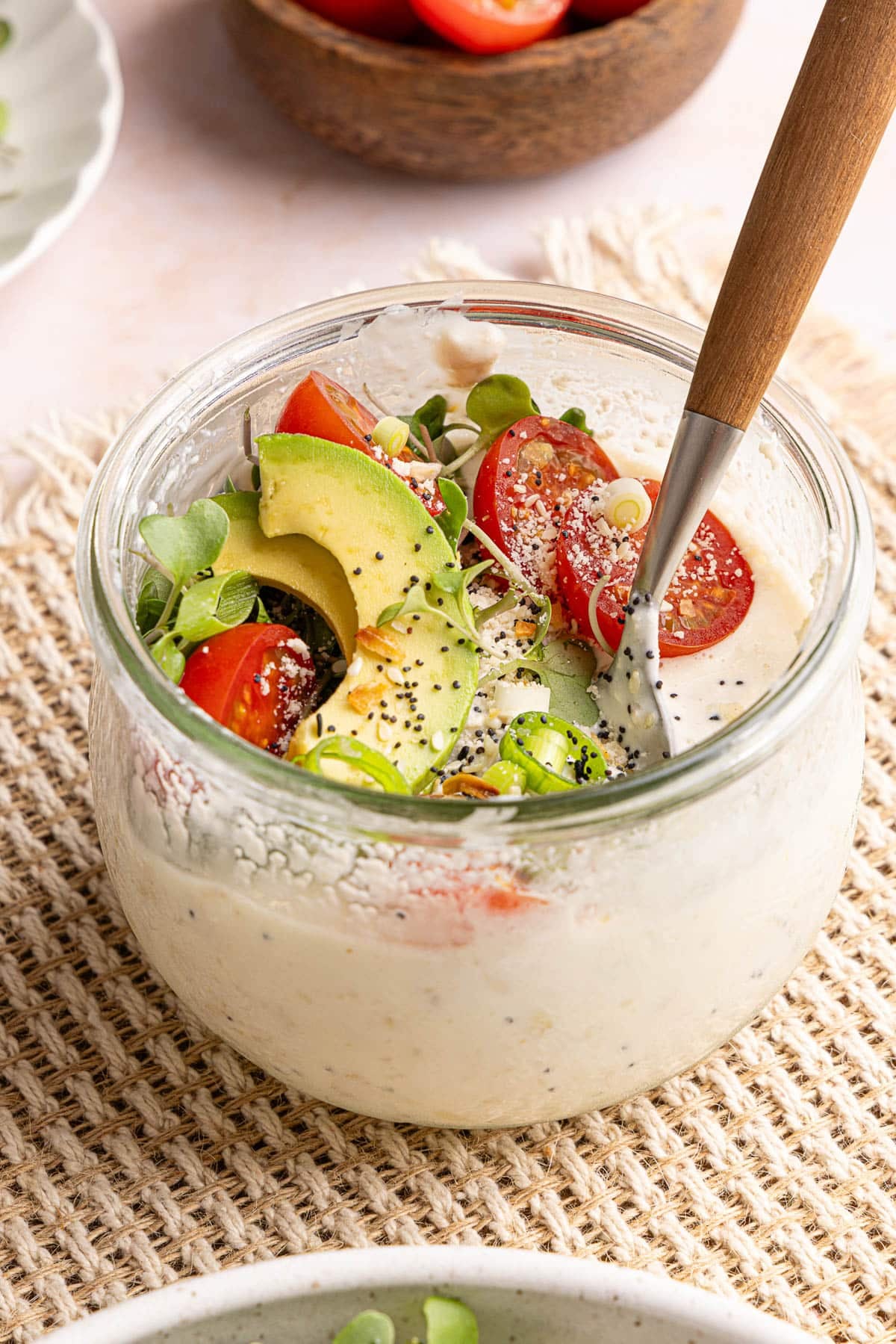 A spoon rests in a container of savory overnight oats.