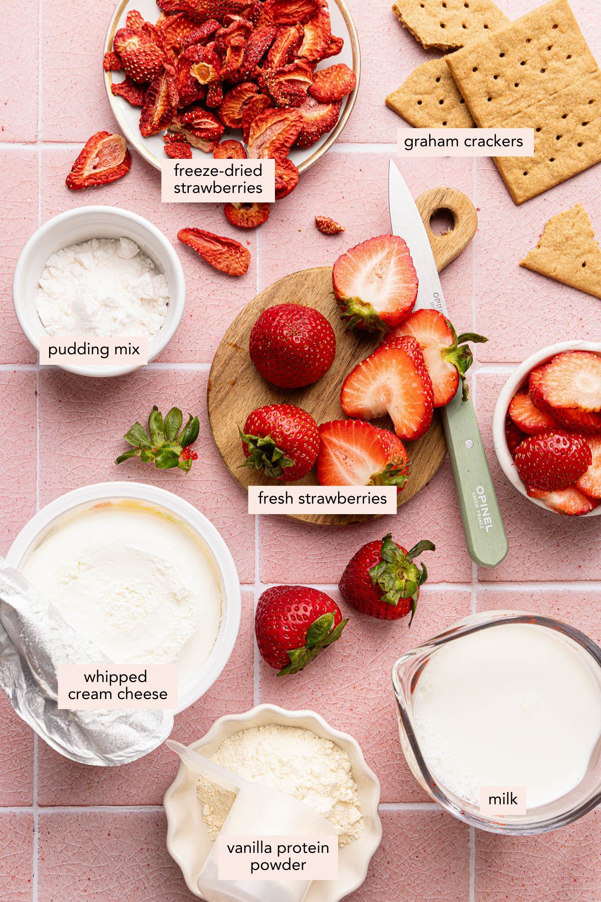 All of the ingredients for ninja creami strawberry cheesecake ice cream in bowls on a countertop.