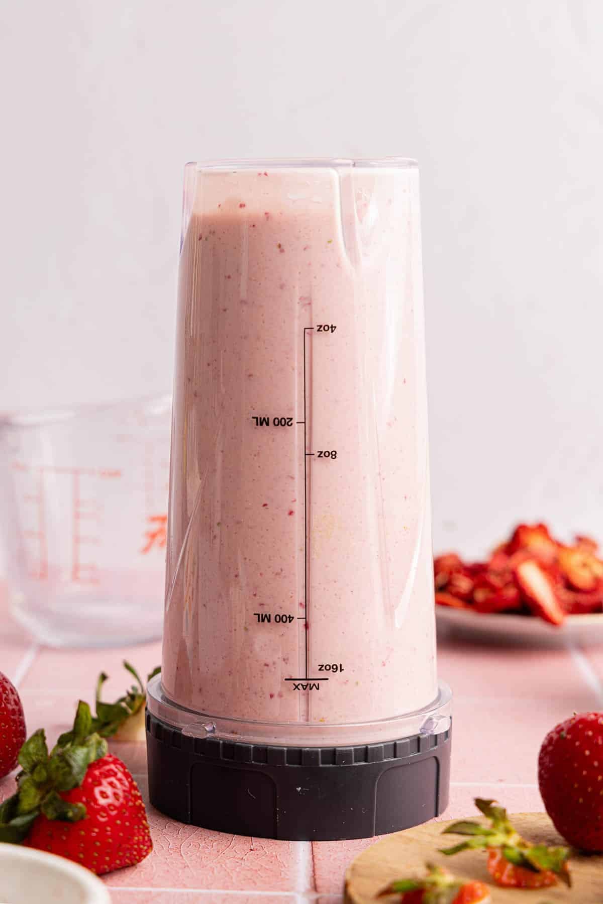 All of the ingredients for strawberry cheesecake ice cream in a blender container after blending.