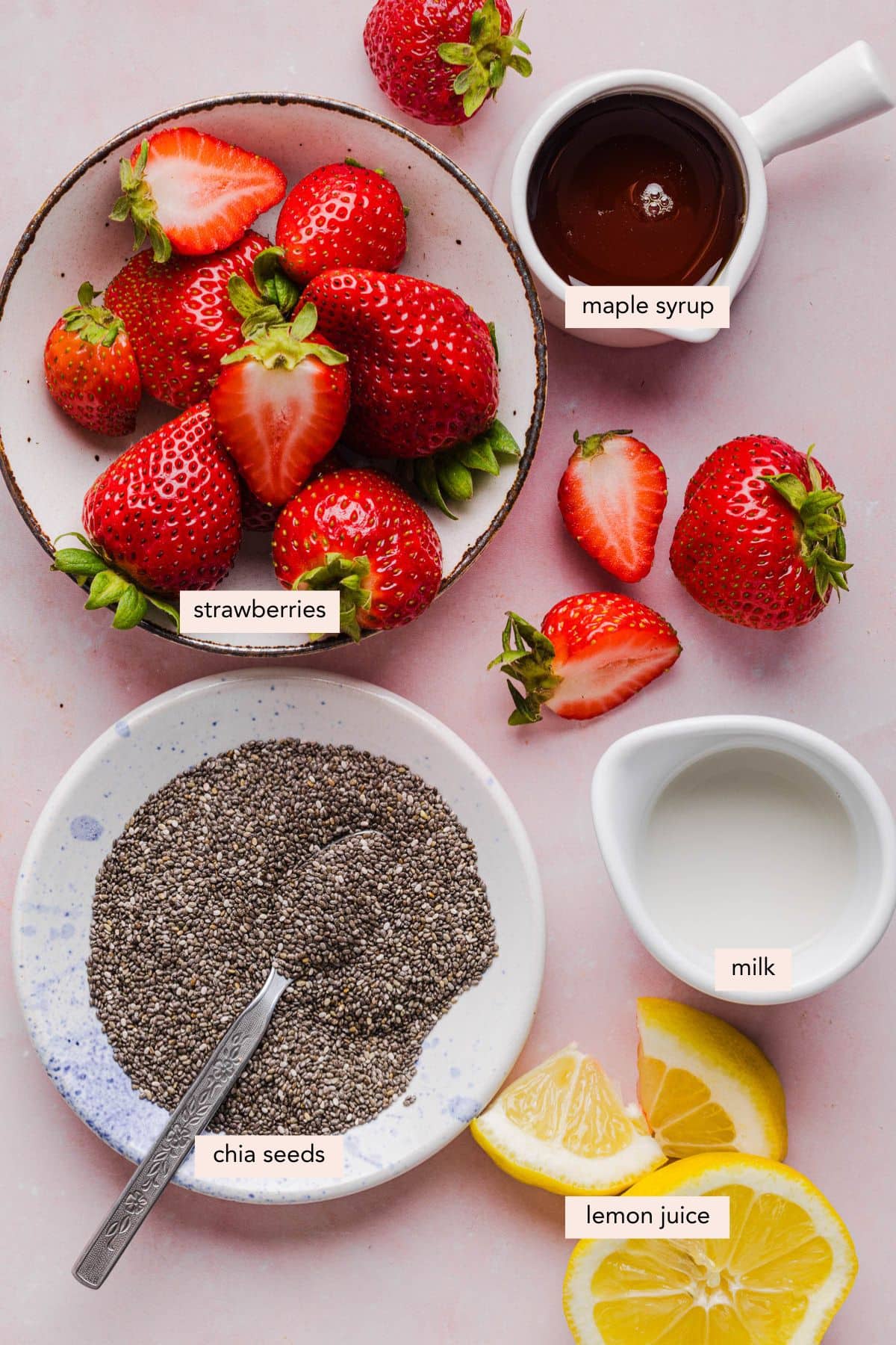 All of the ingredients for strawberry chia pudding in bowls on a countertop.