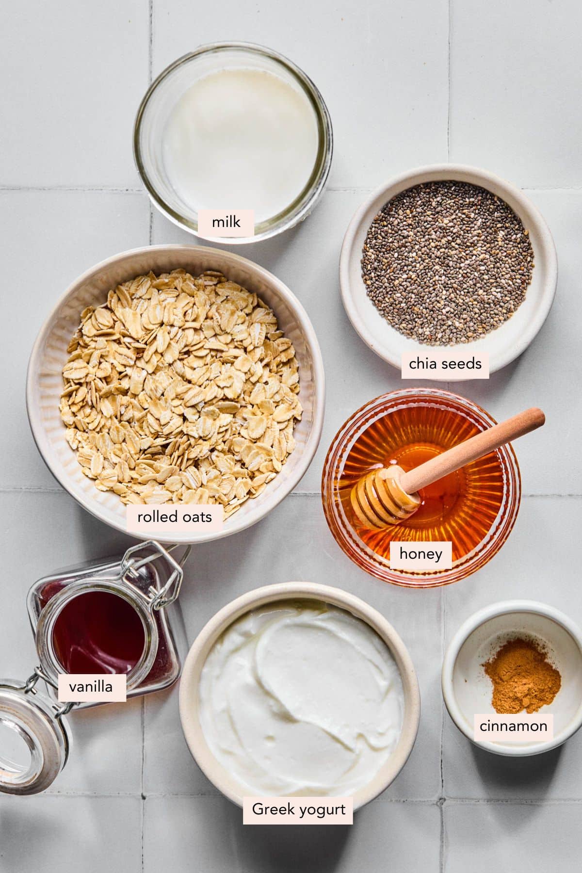 All of the ingredients for vanilla overnight oats in bowls on a countertop.