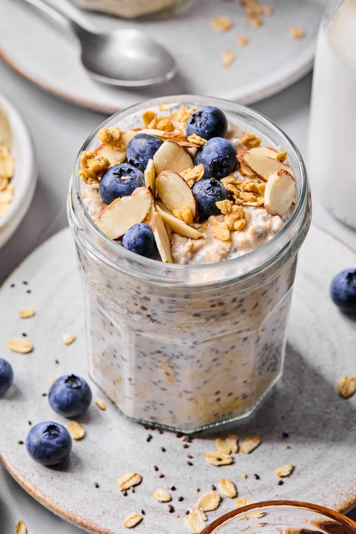 A jar filled with vanilla overnight oats and almonds, granola, and fresh blueberries for topping.