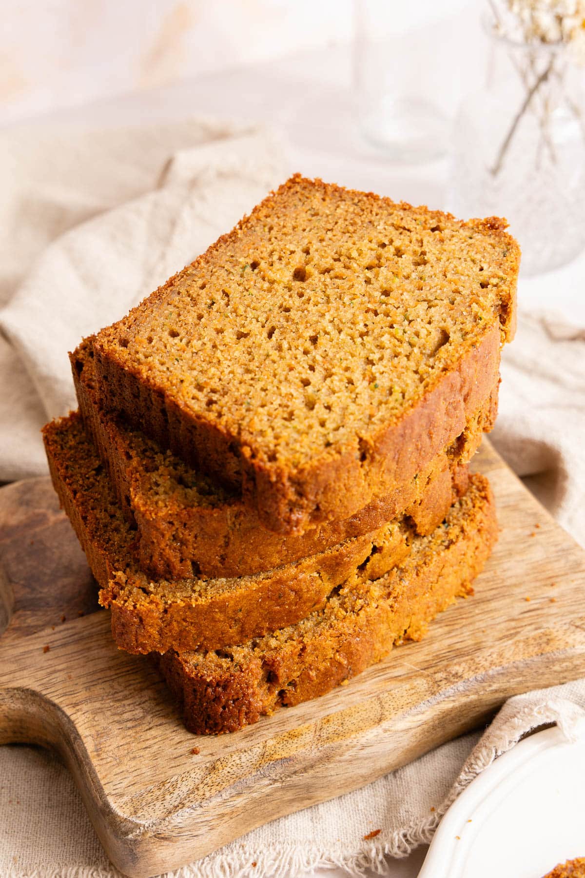 Four slices of zucchini carrot bread in a pile on a wooden cutting board.