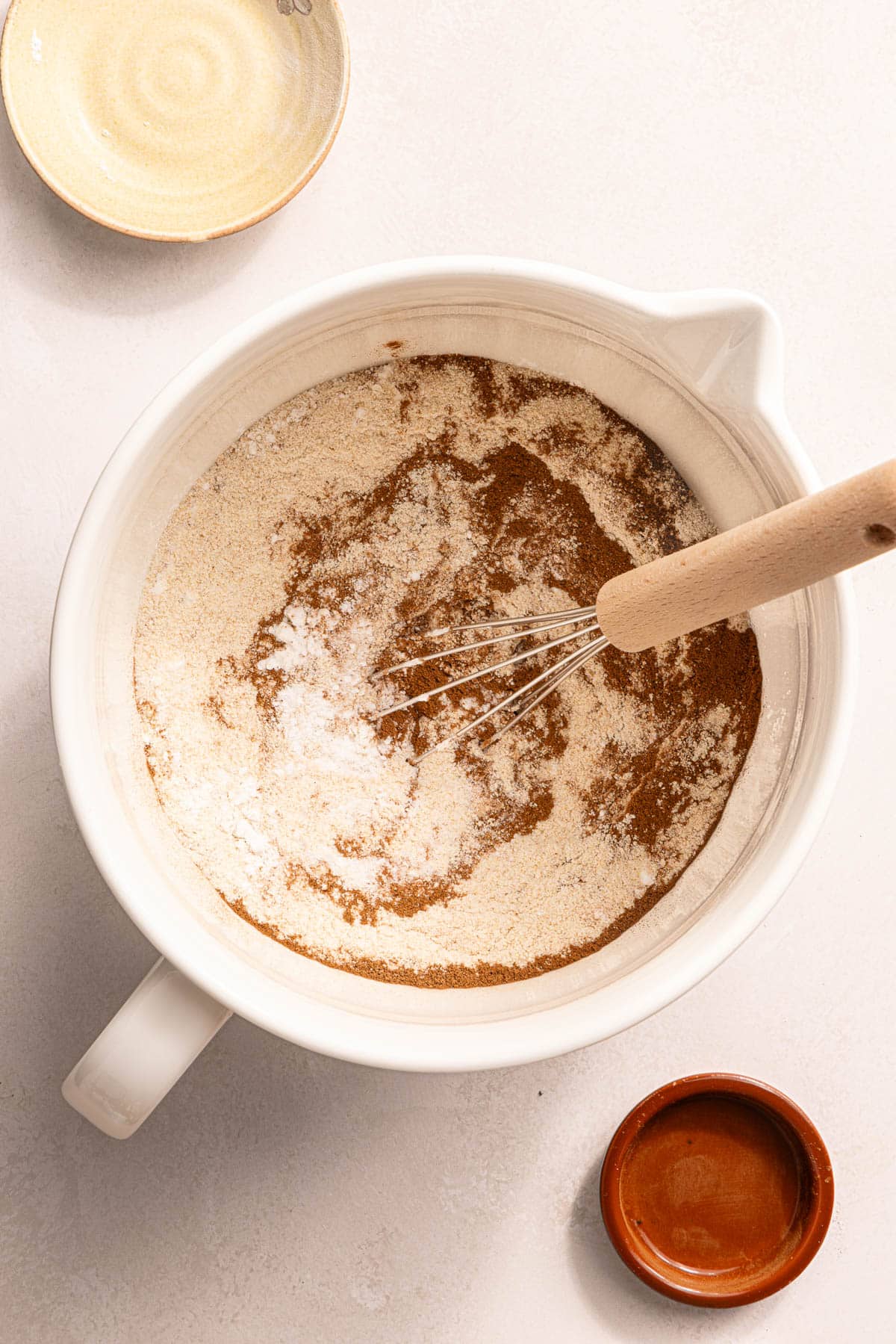 A whisk rests in the mixing bowl with the dry ingredients.