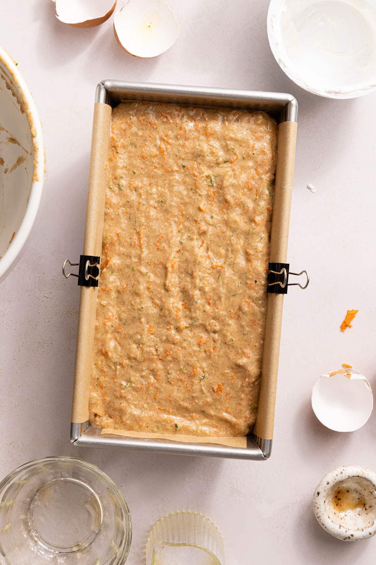 The bread batter poured into a load pan lined with parchment paper.