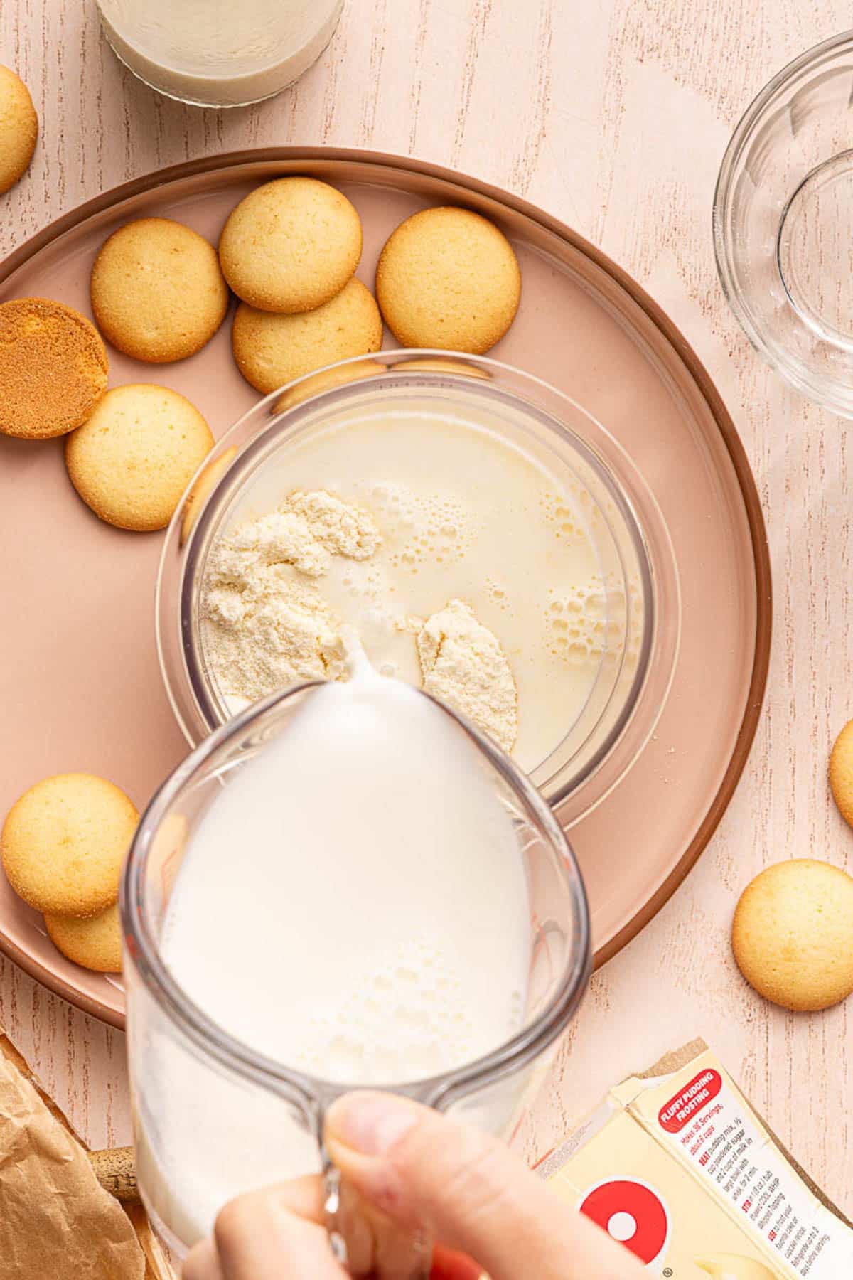 A hand pours the milk into the ninja creami container with the other ice cream ingredients.