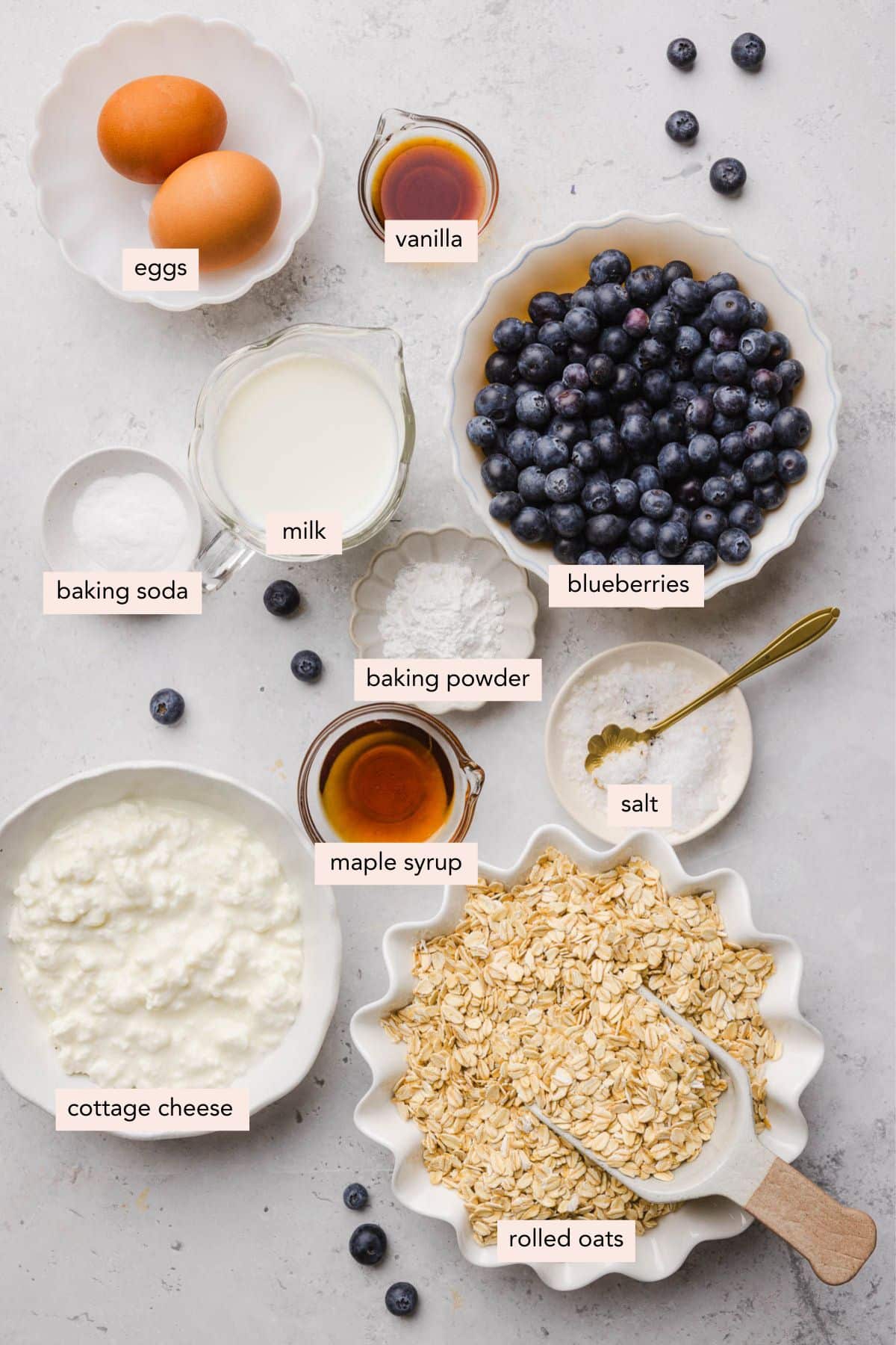 All of the ingredients for blueberry cottage cheese pancakes in bowls on a countertop.