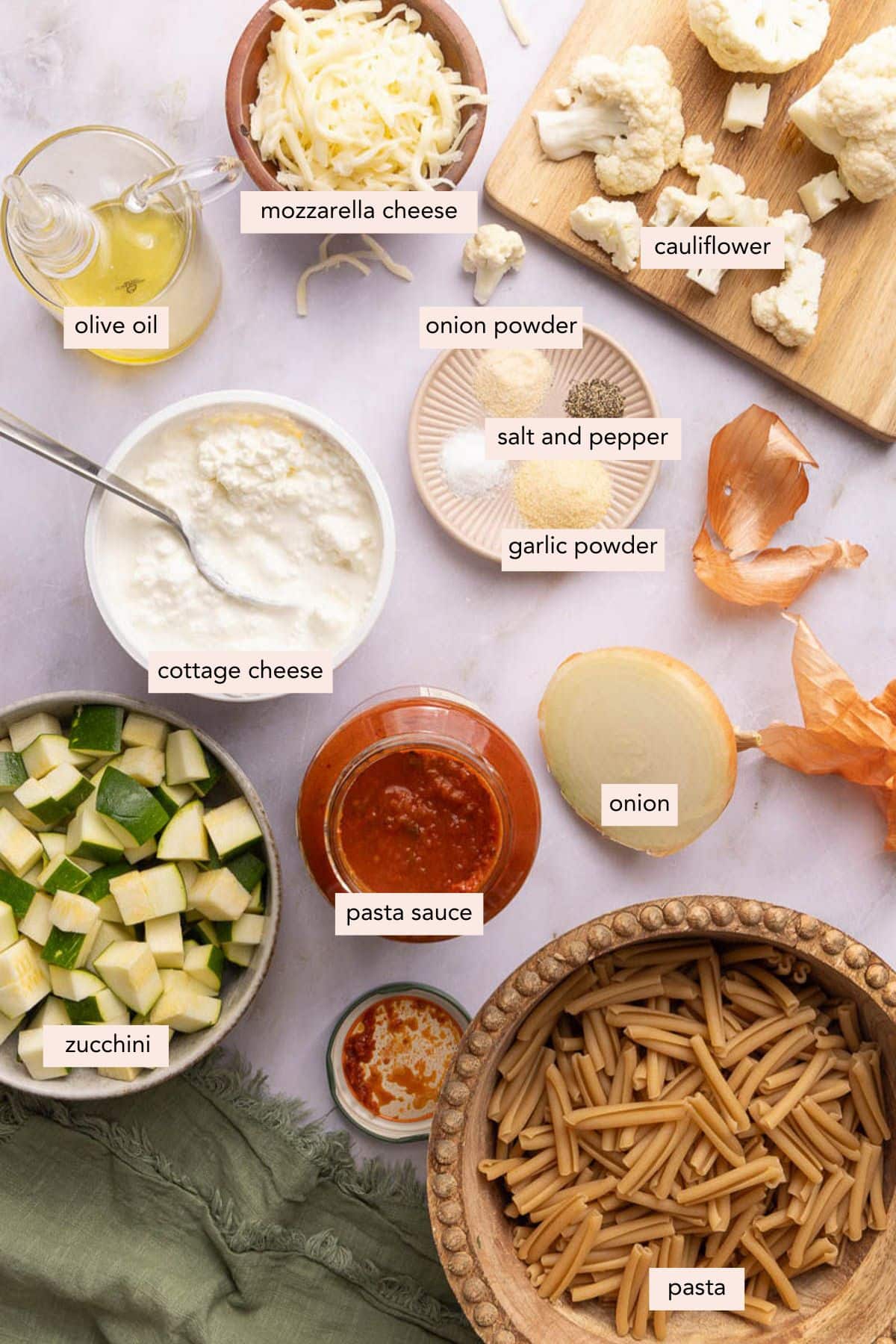 All of the ingredients for cottage cheese pasta bake in bowls on a countertop.