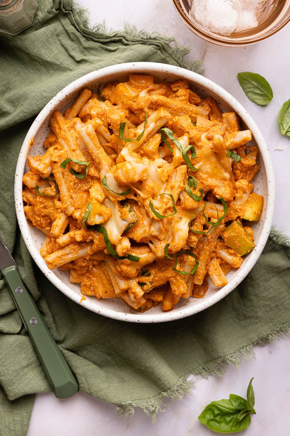 A shallow bowl filled with the baked cottage cheese pasta on a table with a green cloth napkin.