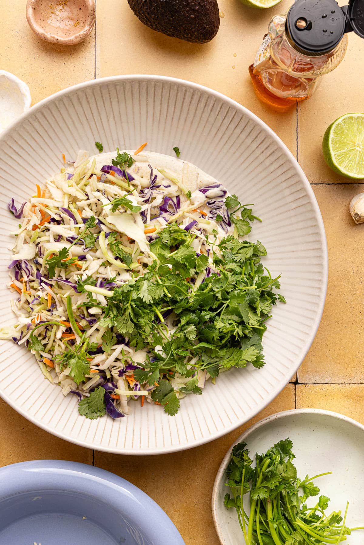 The coleslaw mix and cilantro in the bowl with the slaw dressing before mixing everything together.