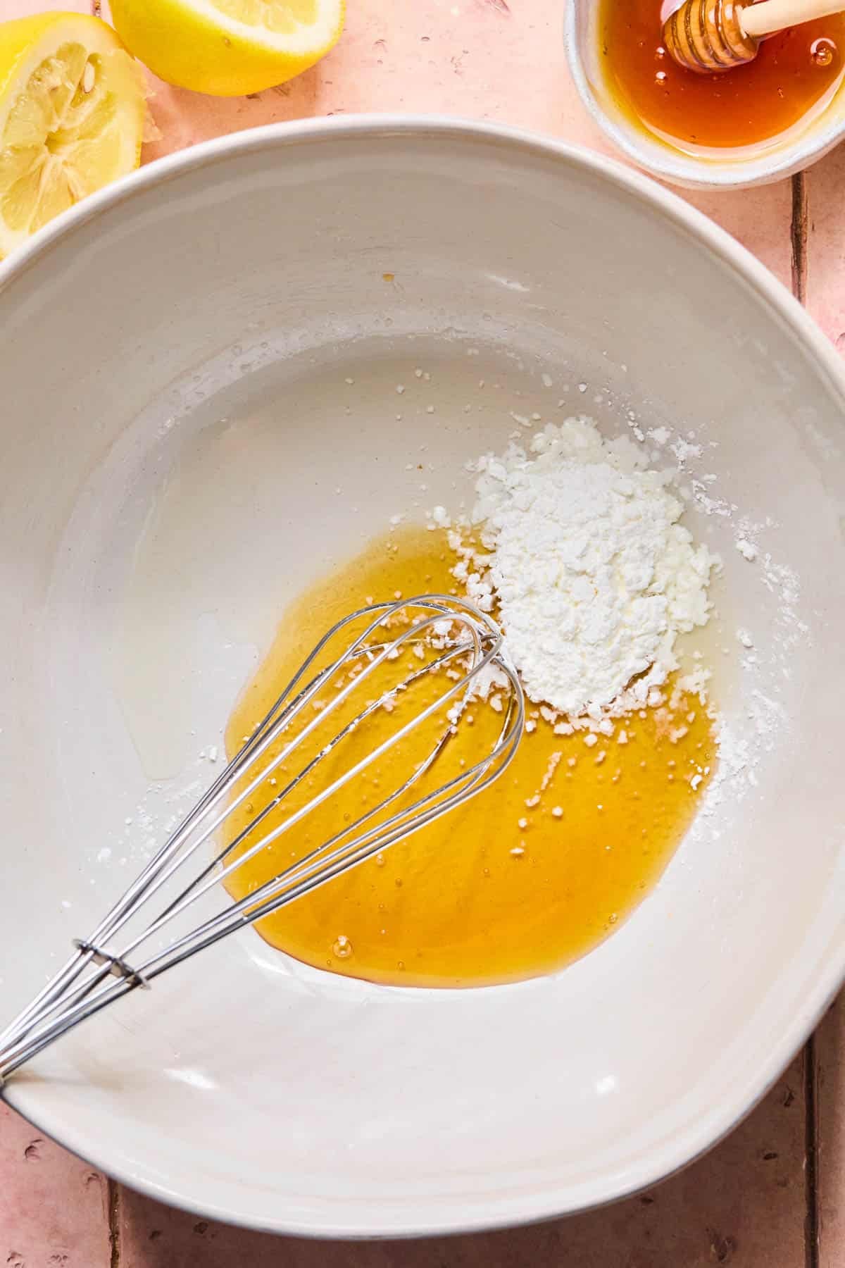 Lemon juice, honey, and cornstarch in a white bowl before whisking.