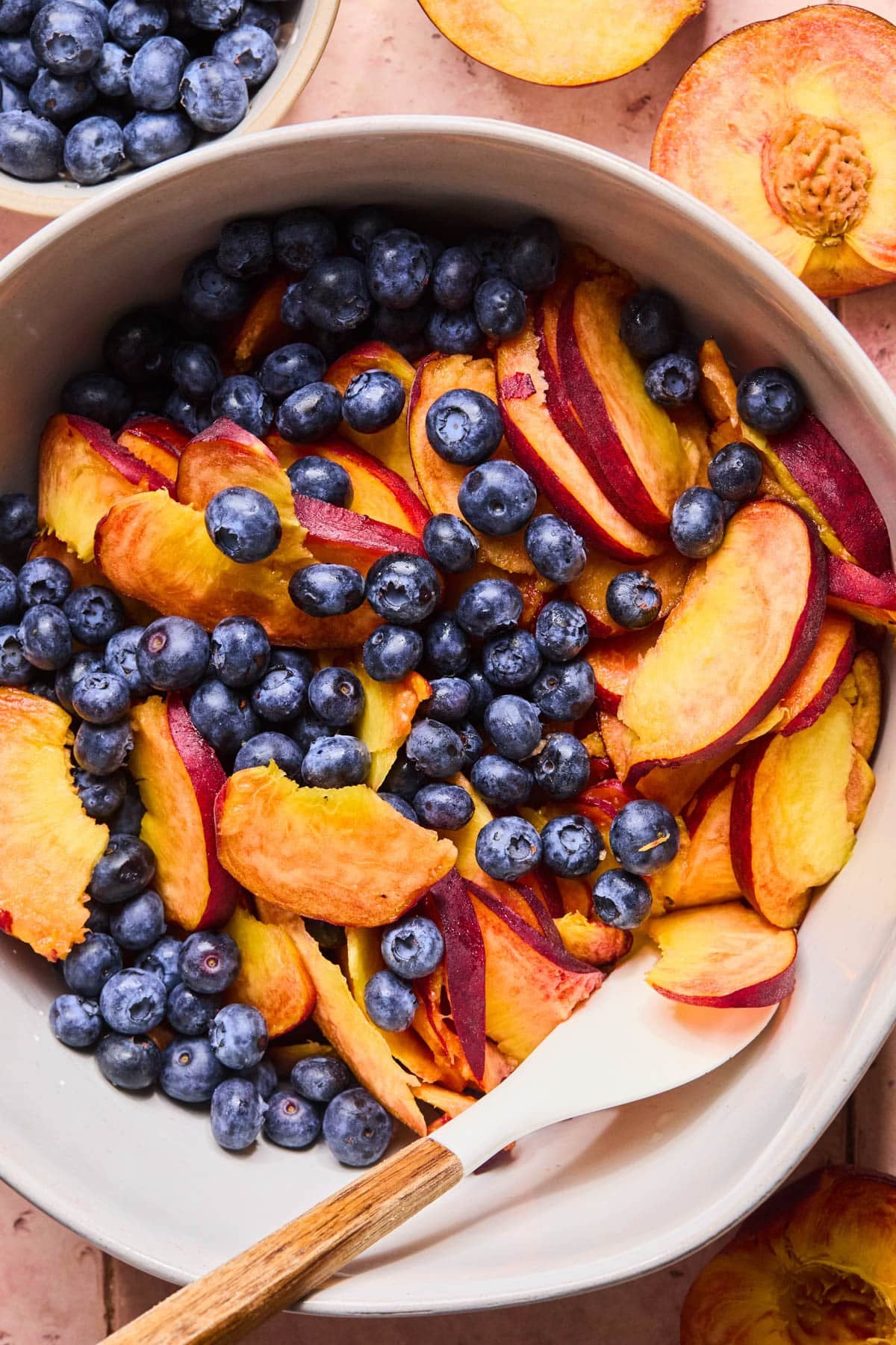 Blueberries and peaches in the bowl with the whisked cornstarch mixture.