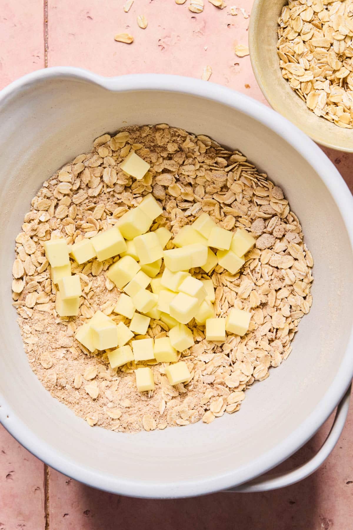 The diced butter in the white bowl with the whisked dry ingredients.