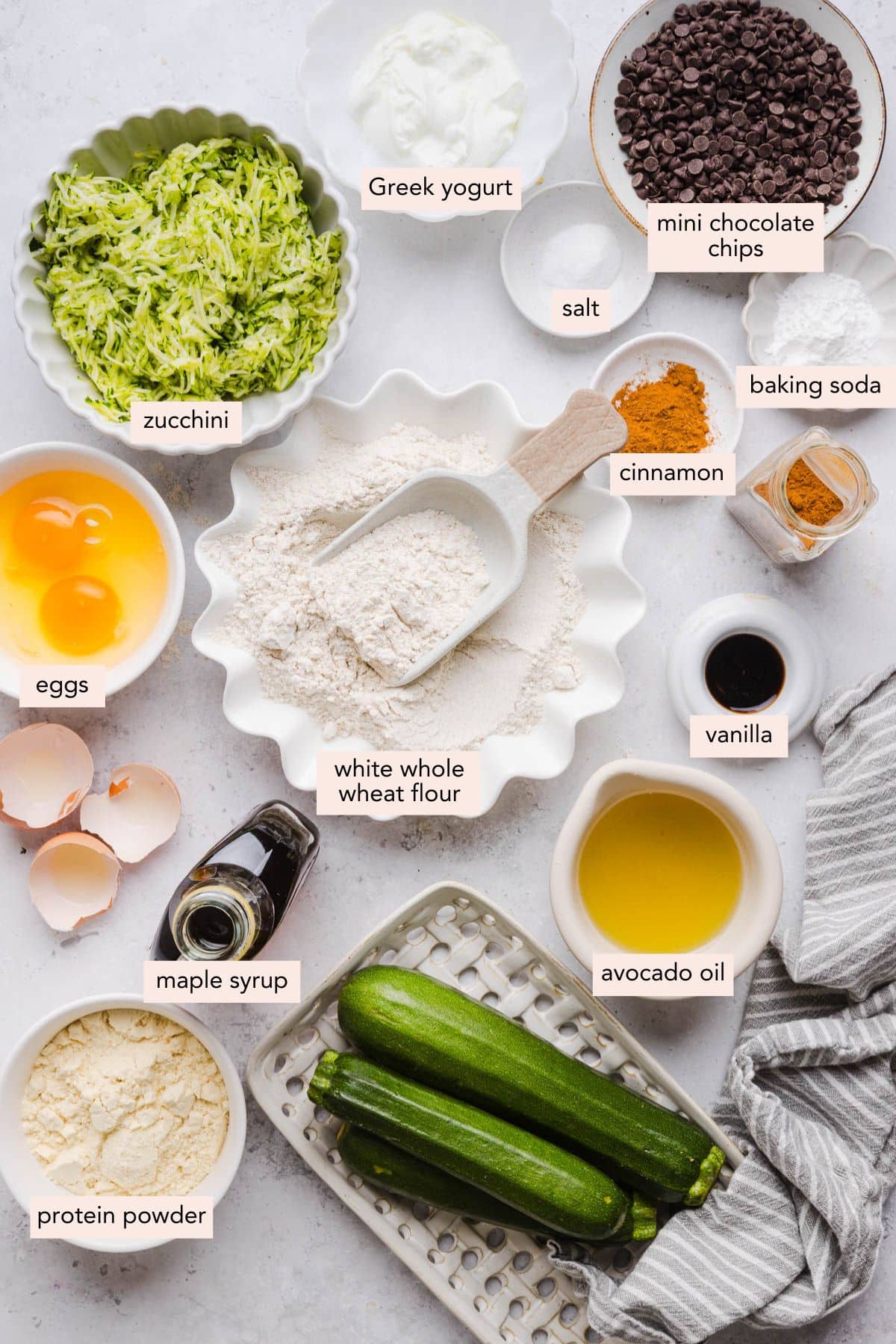 All of the ingredients for protein zucchini bread in bowls on a countertop.
