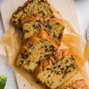 Four slices of protein zucchini bread on parchment paper on a countertop.